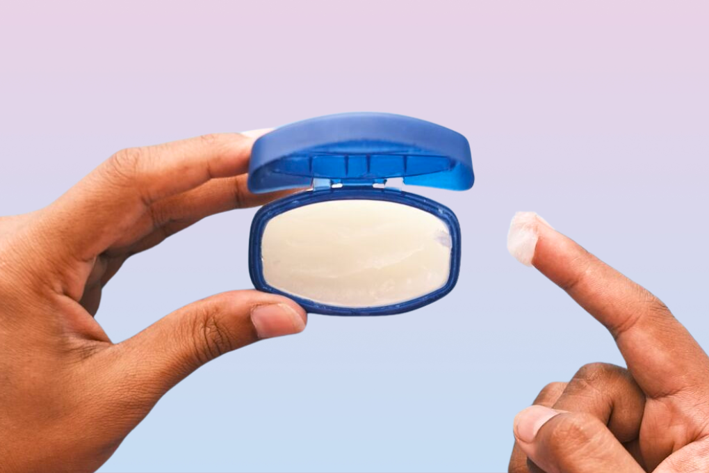 Hands scooping out petroleum jelly from tub